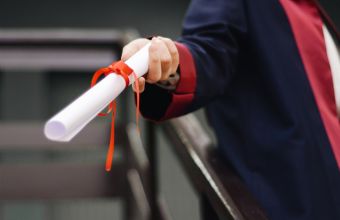 Hand hält gerolltes Sprachzertifikat